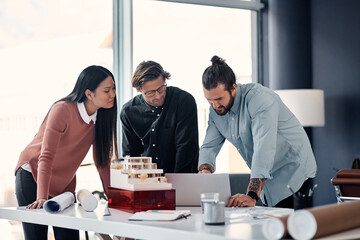 Canvas Print - Architect, team and meeting with laptop for design, planning or brainstorming for construction at office. Group of creative employees or civil engineers in discussion on computer for building startup