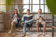 © InsideCreativeHouse - Group of people in smart casual sitting on chairs and preparing before a job interview with folder and gadgets in hands in office corridor. Applicants waiting for employment hiring process