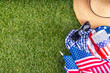 July 4, Independence Day traditional American picnic background. Plates, glasses, USA flags on green lawn or meadow grass, with blanket or tablecloth for picnic, sunglasses, copy space top view