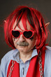 Portrait of an old harmless elf wearing red heart-shaped sunglasses.
