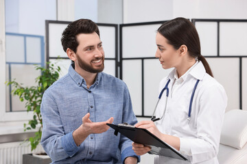 Canvas Print - Doctor with clipboard consulting patient during appointment in clinic