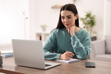 Poster - Young woman watching webinar at table in room