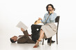 © master1305 - Emotional young woman in retro clothes talking on vintage phone while man lying on floor and reading papers. Business and partnership. Concept of retro and vintage, fashion, cooperation, teamwork
