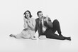 © master1305 - Monochrome i,age of elegant young woman and stylish man sitting on floor and expressively talking on vintage rotary phone. Concept of retro and vintage, fashion, business, human emotions, style