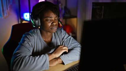 Canvas Print - In a dim gaming room, young black woman with dreadlocks, her arms crossed in skeptical disapproval, battles nerves while playing the game, her face marked with a negative expression.