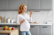 © Prostock-studio - Happy pregnant lady eating yogurt at kitchen