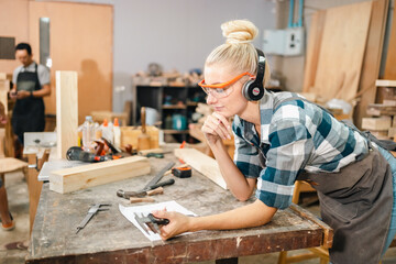 In the carpenter's shop, a professional woman crafts wooden furniture, using tools with skill in her woodwork occupation, showcasing industry prowess.