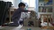 Small boy playing in bedroom with toy castle at home wearing pajamas. Child engrossed in imaginative play in the morning play
