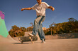 Active young man riding skateboard in skate park on sunny day. Extreme sport concept