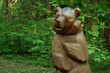 wooden figure bear in summer park, nature background. bear sculpture made of wood.