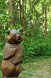wooden figure bear in summer forest, nature background. cute bear sculpture made of wood.