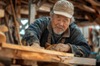 © Rattanapon - Senior Asian carpenter working with equipment on wooden table, building his house.
