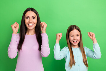 Canvas Print - Portrait of two people mother daughter raise fists shout yes isolated on bright green color background