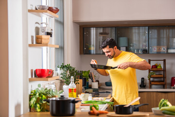 Indian asian man in kitchen cooking alone and having fun.