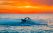 A man on jet ski jump on the wave at amazig sunset 