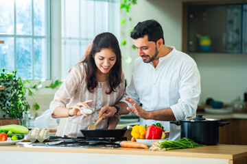 Indian couple in kitchen - Young Beautiful asian wife enjoying cooking with husband.