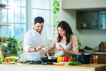 Indian couple in kitchen - Young Beautiful asian wife enjoying cooking with husband.