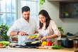 © StockImageFactory - Indian couple in kitchen - Young Beautiful asian wife enjoying cooking with husband.