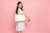 Fototapeta  - Happy Asian woman holding white textile eco bag or cloth bag isolated on pink background, Ecology or environment protection concept