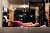 Fototapeta Kwiaty - A sportswoman is lying on the mat and doing exercises for abs.