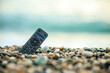 A remote control is laying on the beach