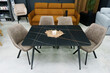 Black wooden table complete with beige wooden chairs with soft fabric upholstery. White candle on the table