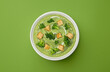 Broccoli cream soup with croutons on green background, top view