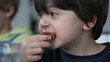 Close-up face of small boy eating bread with jelly for breakfast, candid kid snacking carb food