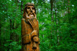 wooden pagan idol in forest, abstract natural background. old god totem in Slavic folk style form of bearded old man with wheat in his hands. Attribute of pagan religious rites