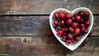 Heart Shaped Bowl Filled With Cherries on Wooden Table