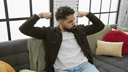 Poster - Confident young man proudly flexes his muscular arms at home, smiling broadly- a positive symbol of fitness and powerful energy