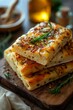 Stack of freshly baked focaccia with sesame and herbs on a wooden board, kitchen background