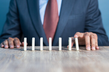 Wall Mural - Business man stoping domino effect by his hand, business strategy background image, wearing blue suit and red tie