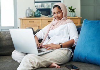 Wall Mural - Muslim, woman and couch to relax on laptop at home in living room with digital technology for online content. Traditional, islam and hijab person on internet to connect to culture for Eid blog