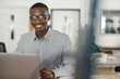 African businessman smiling while using a laptop in an office
