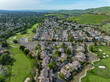 Drone photos over the Oakhurst neighborhood in Clayton, California with green hills, golf course and homes.