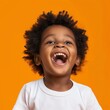 Joyful African American child with a radiant smile and bouncy curls against a sunny orange backdrop, epitomizing pure happiness.