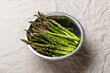 Green asparagus in a metal bowl on a linen tablecloth