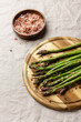 Green asparagus with pink salt on a wooden cutting board
