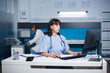 © DC Studio - Cucasian practitioner is typing a medical report at a desk in a hospital office late at night. Female nurse preparing medical care while assessing patient illness symptoms.
