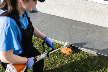 Worker trims grass with electric trimmer tool