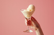 vanilla ice cream in martini glass held by a woman on matching background