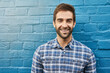 Man, smile in portrait and relax against wall background, casual fashion and positivity with blue aesthetic. Confidence, pride and model in checkered shirt, style and lumberjack outfit in Australia