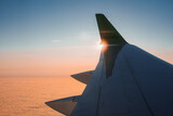 Fototapeta  - Wing of modern Airbaltic aircraft flying in cloudy sunset sky during a trip