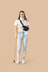 Sticker - Injured young woman after accident with crutch on brown background