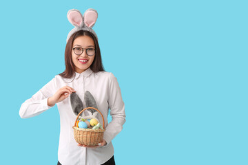 Sticker - Young Asian businesswoman in bunny ears with Easter eggs on blue background