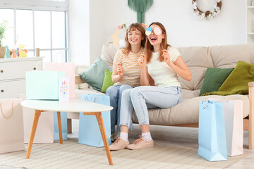 Wall Mural - Happy young women with paper shopping bags and decor for Easter at home