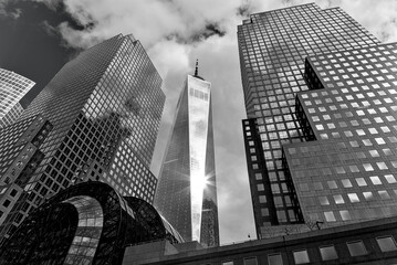 downtown manhattan skyline view (sun flare shining from one skyscraper) trade center (world place) glass high rise tower downtown new york city travel destination office tower detail looking up sky