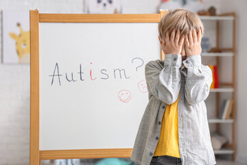 Wall Mural - Stressed little boy and board at psychologist's office. World Autism Awareness Day