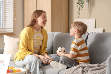 Poster - Female psychologist working with little boy on sofa in office. World Autism Awareness Day